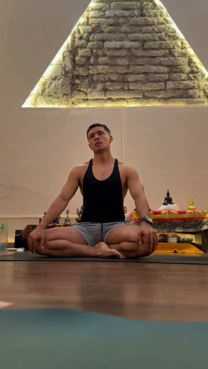 Miguel Díaz sentado en padmasana sobre un tapete, practicando respiración alterna.